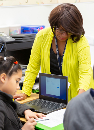 Photo: Teacher helping student with computer